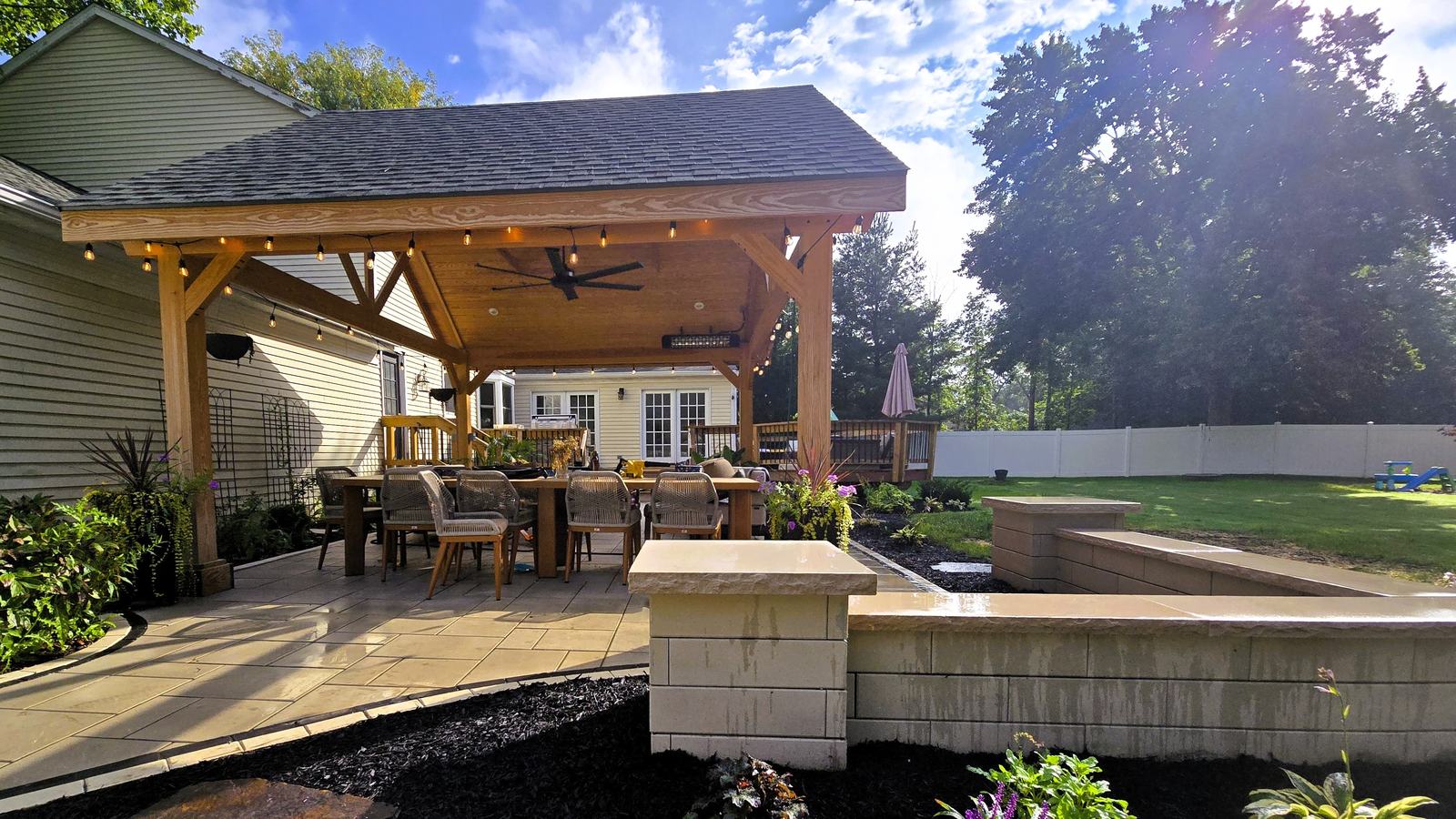 Covered pavilion with string lights, bluestone patio and seat wall built by Lasting Impressions in Portage County, Ohio